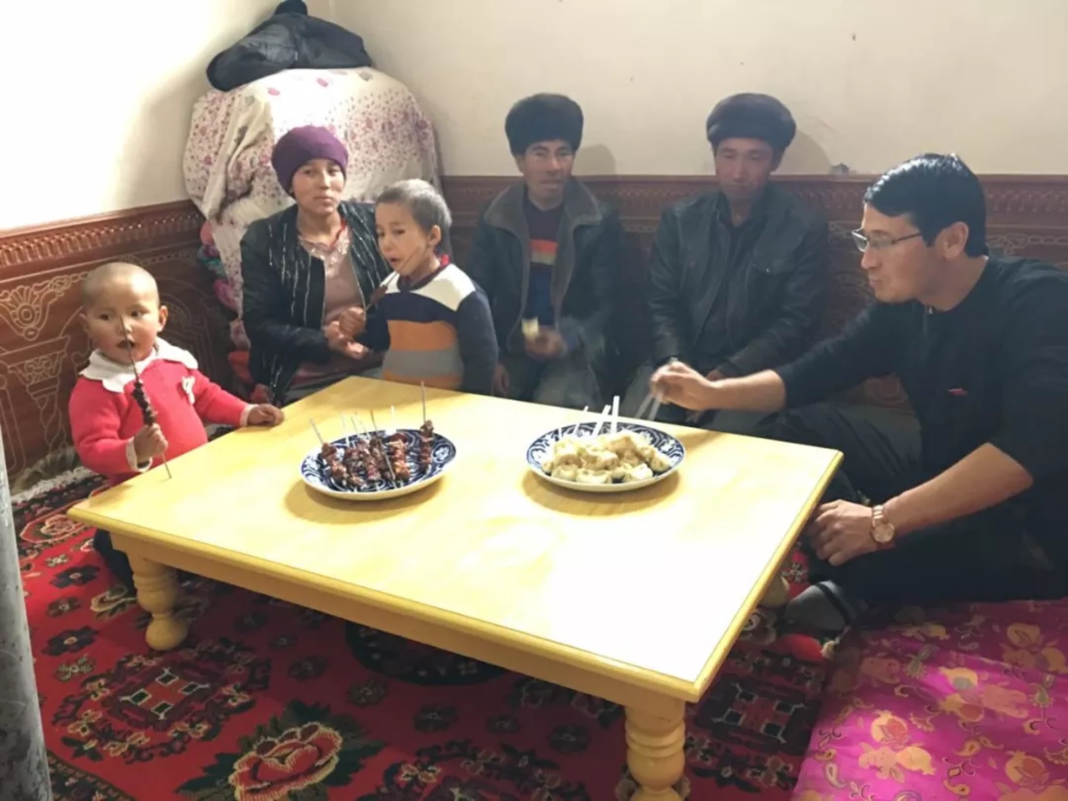 Xinjiang Communist Youth League—WeChat Ziyarete gönderilen bir Han memuru, onlara hediye olarak verdikleri bir masada Uygur ailesiyle birlikte yemek yiyor. Bu görüntü Sincan Komünist Gençlik Ligi tarafından sosyal medya platformu WeChat'ta yayınlandı.