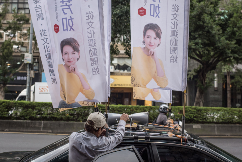 A campaign worker rigs a loudspeaker atop the car of Legislative Yuan candidate Zhou Fang-ru in Taipei.