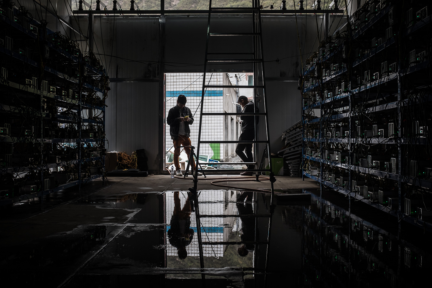 Employees use their phones at the Bitcoin mine, September 26, 2016. The mine has 550 “mining machines” running continuously. They solve complicated mathematical problems for which they are rewarded with Bitcoins. Seven employees work in shifts monitoring the machines to keep the mine running 24 hours a day.