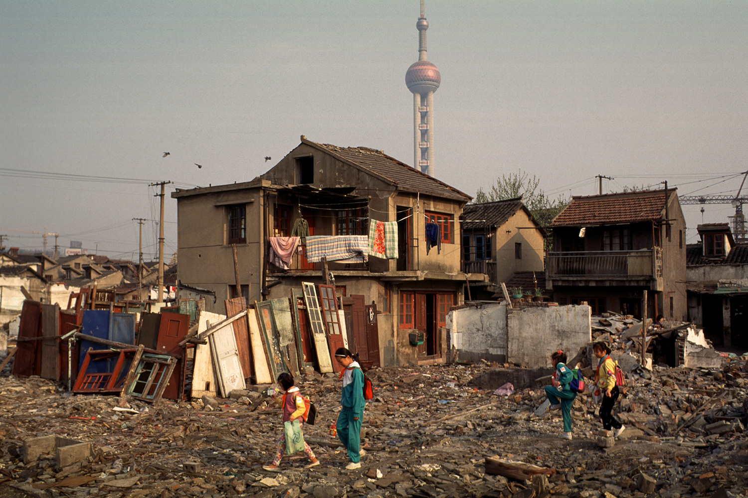 On their way to school, children pass through the rubble of demolished homes in their neighborhood in Lujiazui, 1996.