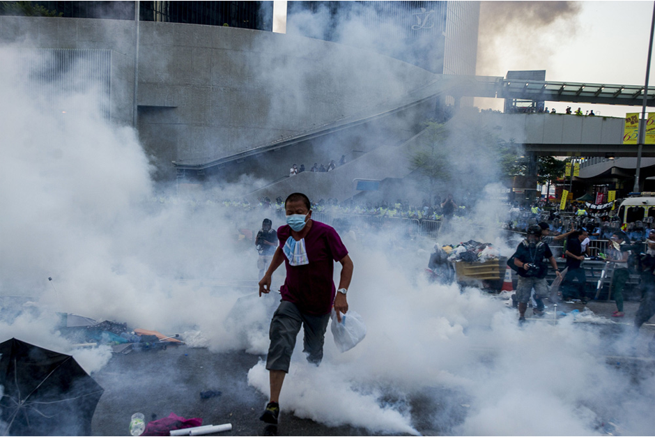 A pro-democracy demonstrator runs as police fire tear gas on September 28 near government headquarters in the Admiralty District. (Photo by Xaume Olleros/AFP/Getty Images)