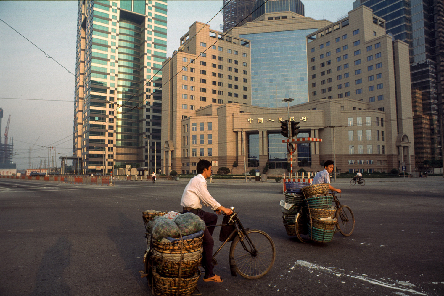Farmers pedal their produce by bicycle past the yet unopened People’s Bank of China, 1996.