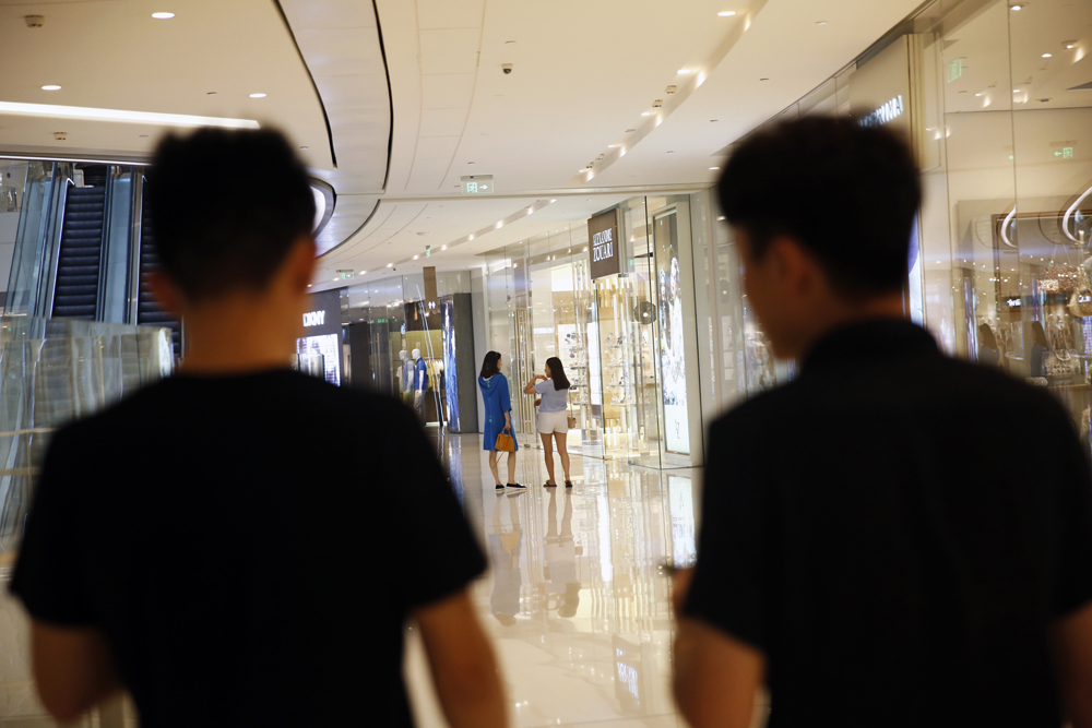 Mentor Lao Tong (left) and a student search for ‘targets’ to approach at a shopping mall, May 17, 2015.