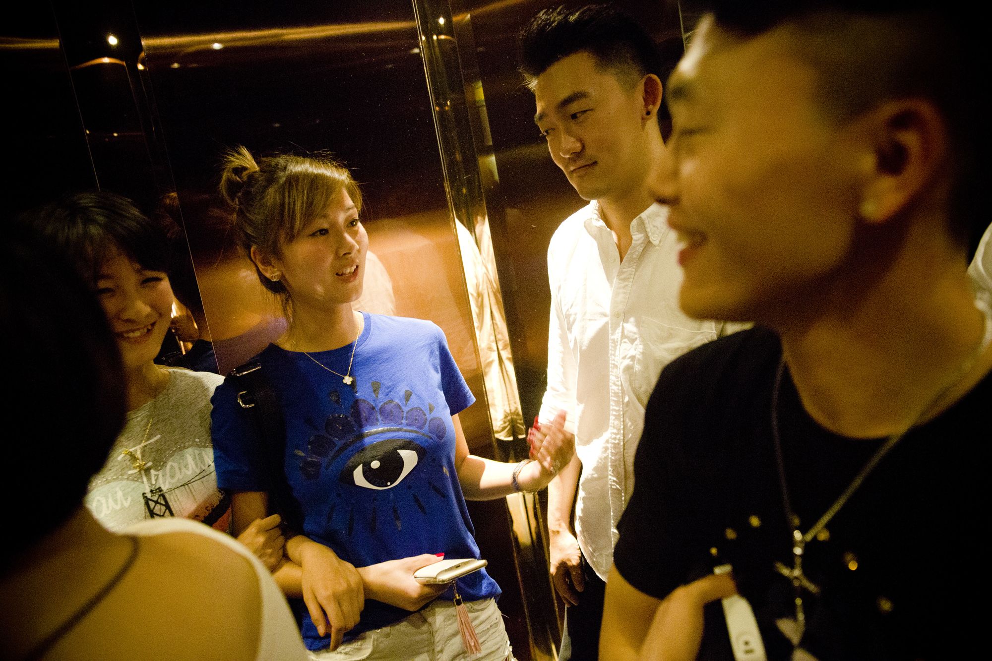 Two mentors chat with women they invited in the elevator as they leave the karaoke bar, just past midnight of May 18, 2015.