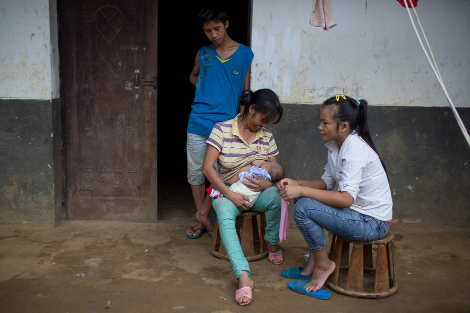 Ming looks on as his mother puts his son’s mouth on her breast in an attempt to calm the child down as Cai looks on. Ming’s mother helps by taking care of the baby most of the time.