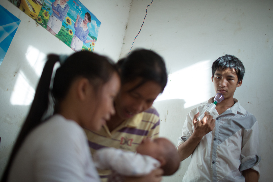 Ming holds a breast pump as he watches his wife, Cai, and his mother care for his newborn at home. “My single friends stopped calling me after I got married, and my life got boring,” Ming said.