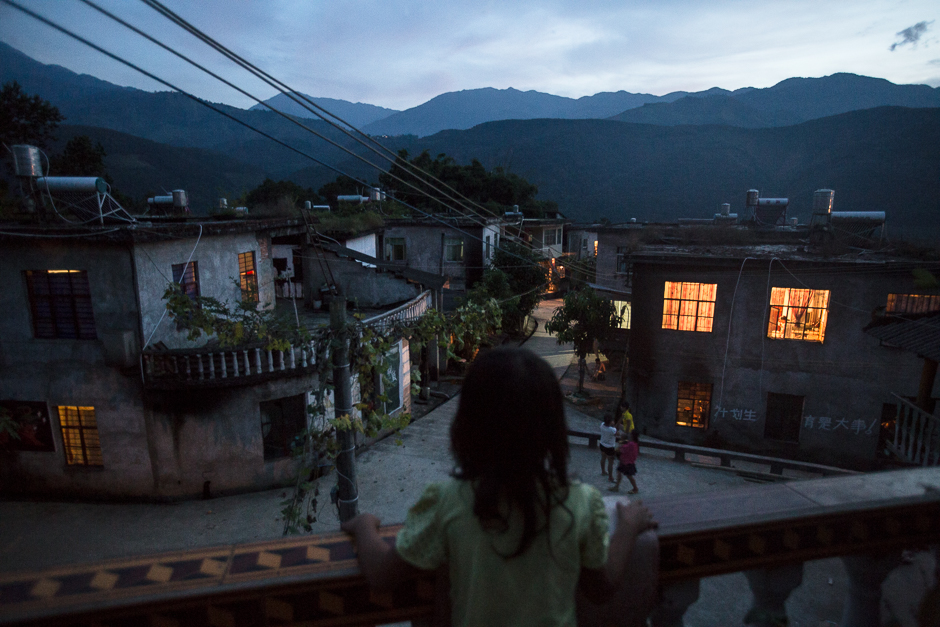 Seven-year-old Yuan looks out over her village from the balcony of a neighbor’s home in Yangxi village, Zhemi county. Yuan has never gone to school because her mother never enrolled her. She said she doesn't know if she ever will go, and says she doesn't know if she wants to.