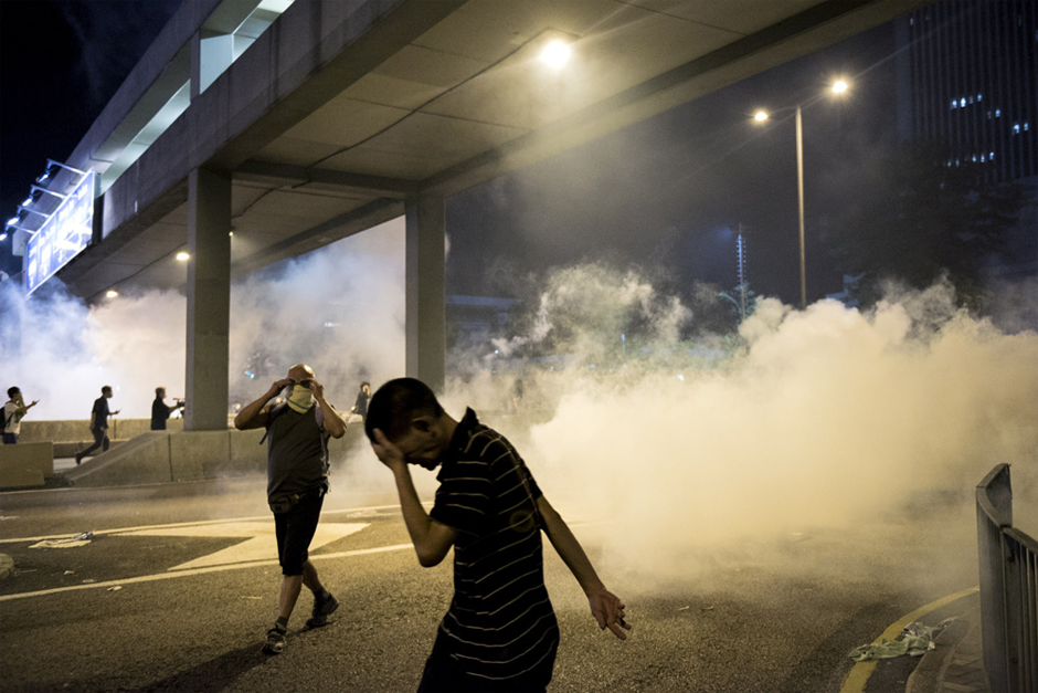 Pro-democracy protesters run away from tear gas fired by the police. (Photo by Alex Ogle/AFP/Getty Images)