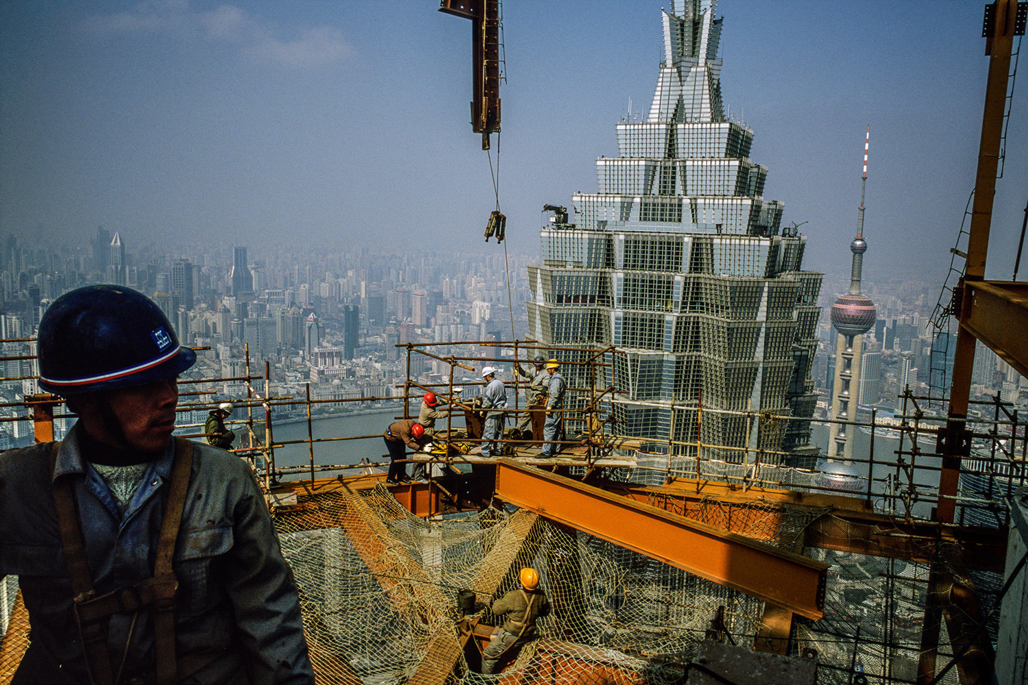 Steel workers from Sichuan set beams on the 88th floor of the Shanghai World Financial Center superstructure under construction in Lujiazui, 2007.