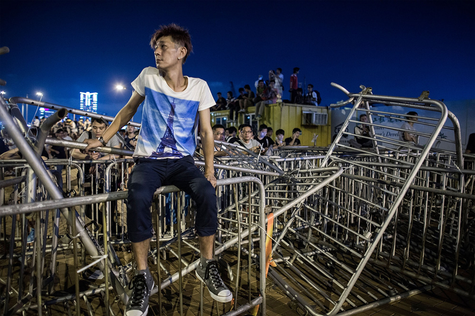 A protester sits on top of barricades used to block the road. (Photo by Lam Yik Fei/Getty Images)