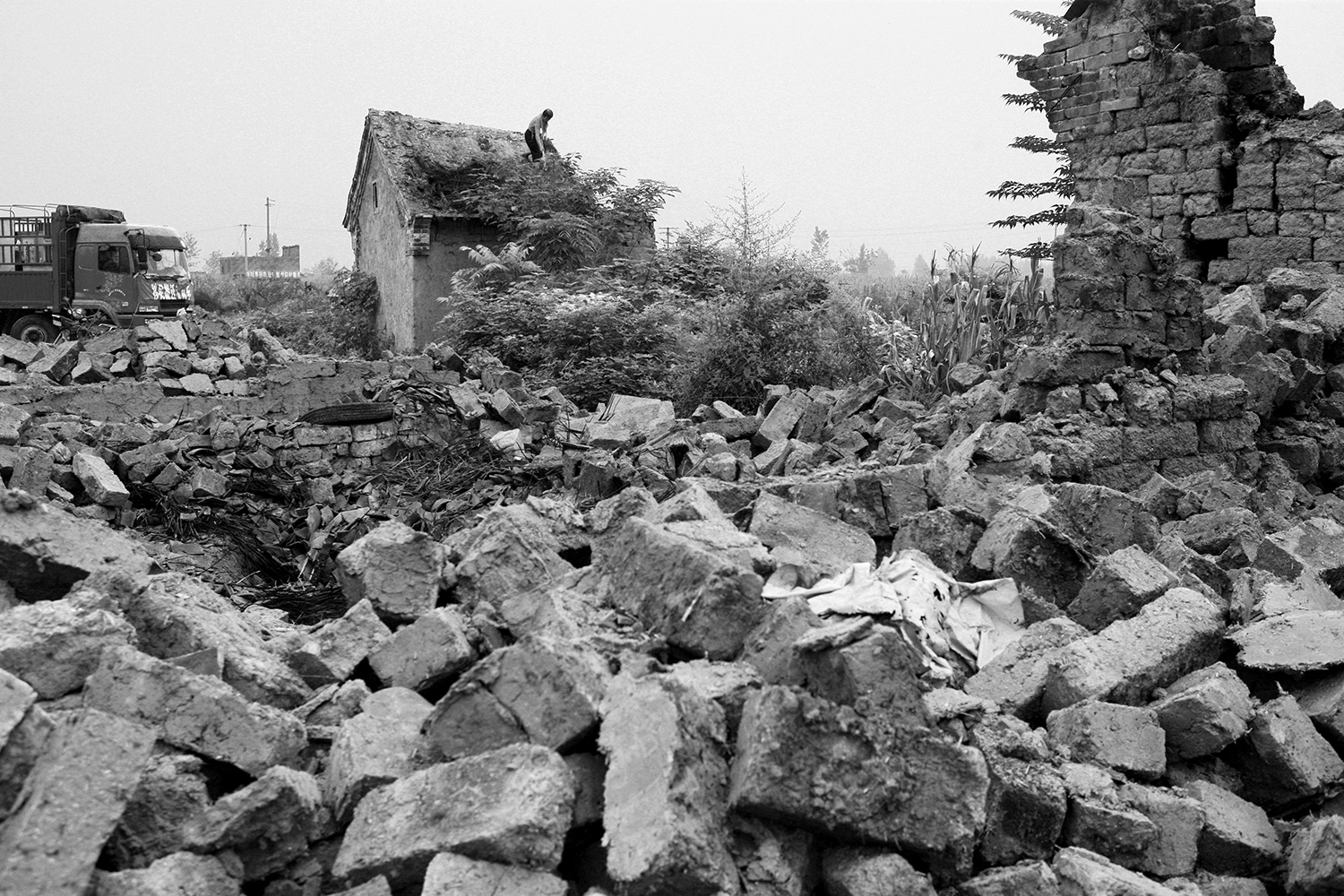 A farmer demolishes his own house in Jinhe. Roof tiles that could be salvaged were loaded onto a truck and taken away.