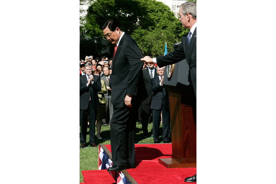 U.S. President George W. Bush attempts to prevent Chinese President Hu Jintao from stepping off the stage during an arrival ceremony at the South Lawn of the White House, April 20, 2006. Hu was on his first official visit to the United States since taking office in 2002. At the same ceremony, a woman in the press box unfurled a banner of the banned spiritual group Falun Gong and shouted at President Bush, “Stop this visit.” Later, the White House announcer mistakenly told the crowd they would now hear the national anthem of “The Republic of China,” the official name for Taiwan. (Photo by Alex Wong/Getty Images)