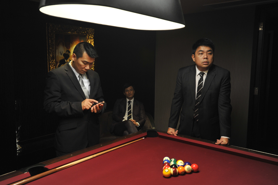 Actors playing a mainland gangster boss and two of his bodyguards rest between scenes of the Johnnie To film <em>Life Without Principle</em>.
