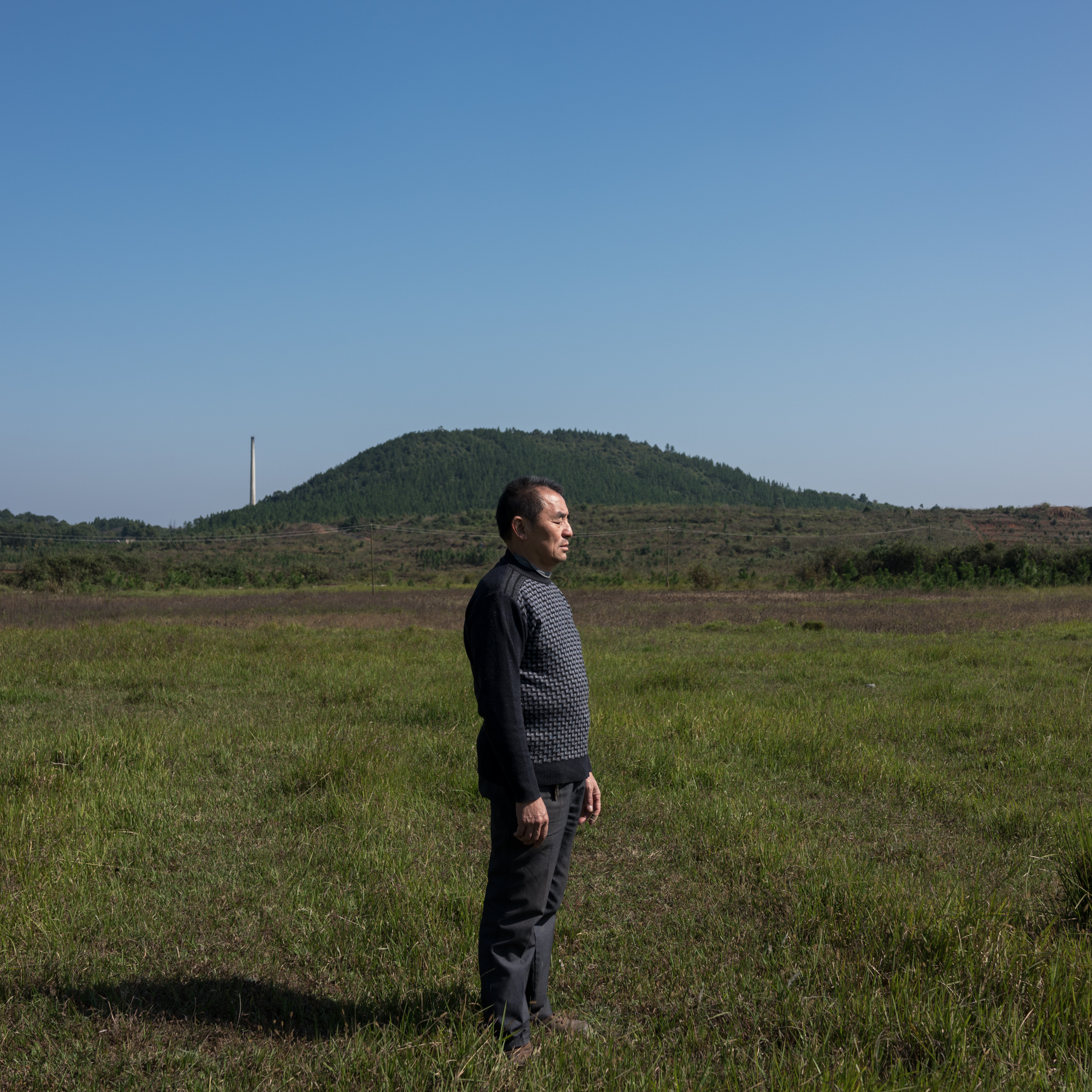 Li Dongde, a school teacher, stands at the execution grounds where his father, Li Jingxi, was shot by militiamen in August 1967. “This is where he was killed and his body lined up with others,” he said quietly before standing for this portrait. “Some of the dead were dumped in the Yongming River because their families didn’t dare collect their bodies.” His father had been accused of being a landlord. Later, he was cleared of any wrongdoing but he has not received redress.