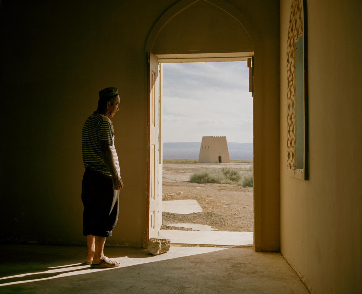A Uyghur man looks through the door of his house, out onto Ayding Lake, in the Turpan Depression, June 2016. The dried up lake is 505 feet below sea level, the lowest point in China. 