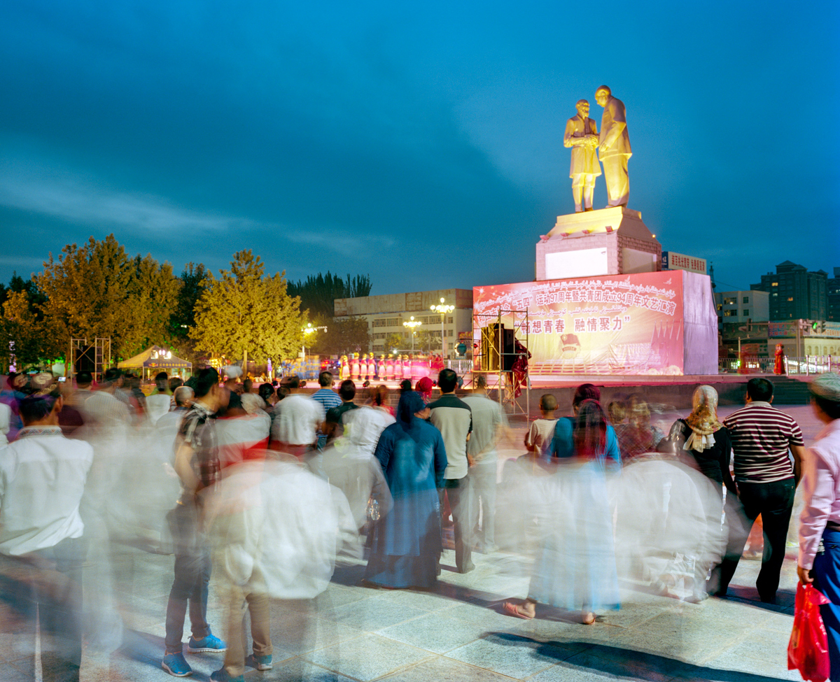 A crowd gathers to watch an event in Tuanjie (or “Unity”) Square, in Hotan, May 2016. A statue of the Uyghur farmer Kurban Tulum shaking hands with Mao Zedong stands in the middle of the square to commemorate their meeting, which the Chinese Communist Party promotes as a symbol of ethnic unity.