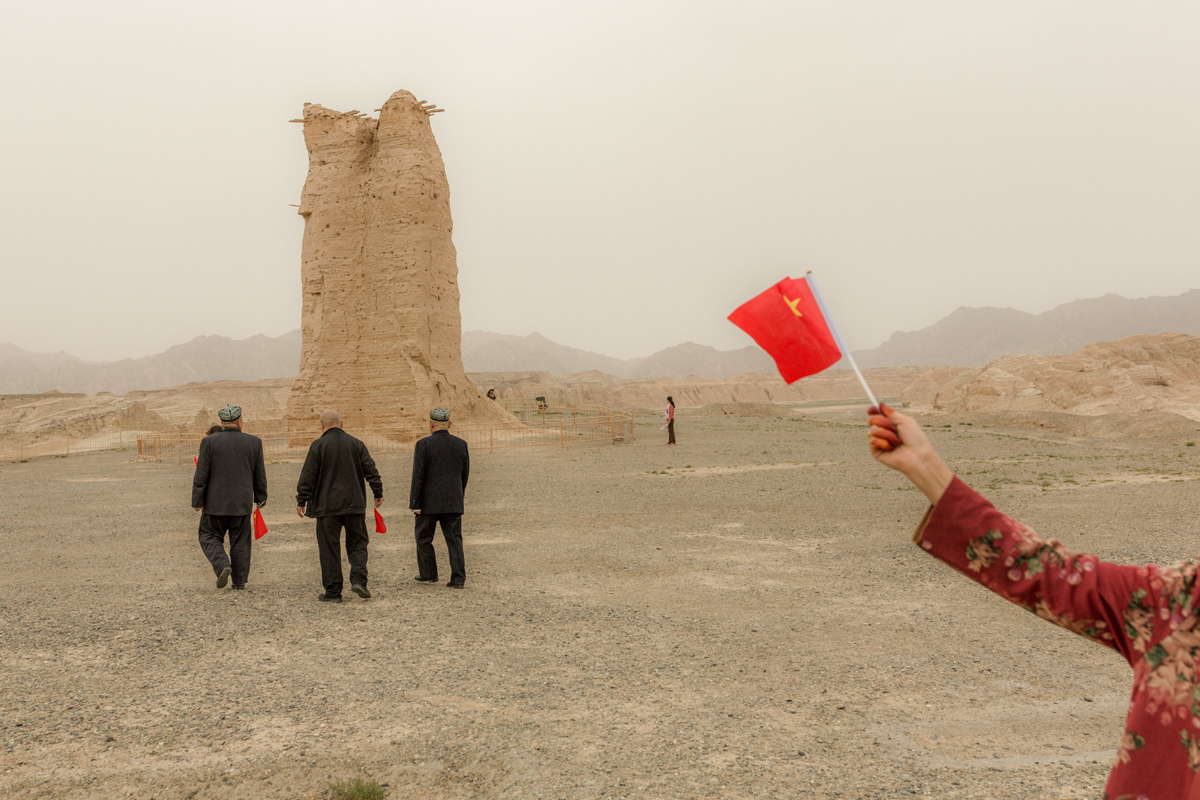 A group of Uyghur tourists holding People’s Republic of China flags visit the Kizil Gaha Beacon Tower, which was built during the Han dynasty (202 BCE-220 CE), in Kuqa, October 2, 2019.