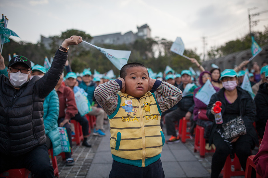 A boy shields his ears from the noise of the crowd at a DPP rally for presidential candidate Tsai Ying-wen in the Shalu district of Taichung.