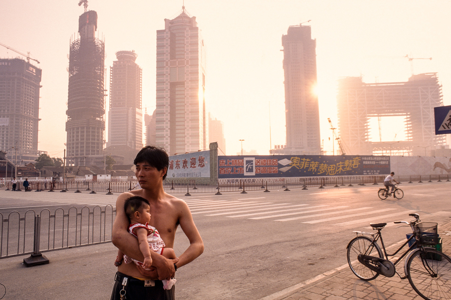 Outside his living quarters in Lujiazui, a construction worker from China’s countryside holds his child, 1996.