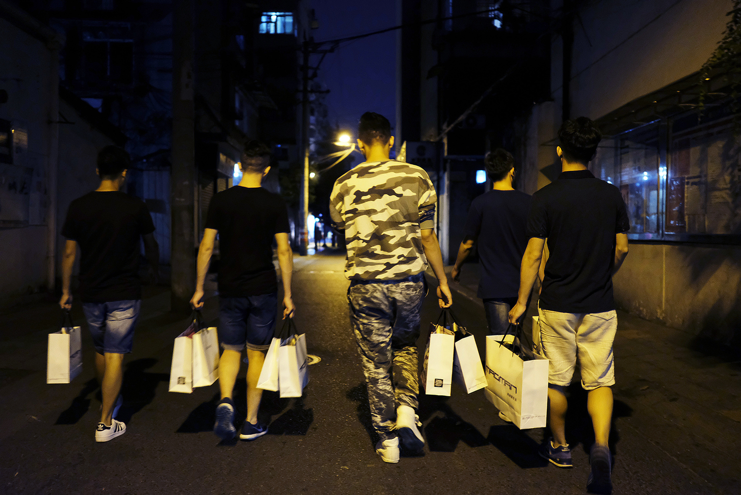 Students head back to their apartment after shopping with mentors on a bustling Chengdu commercial street, October 1, 2016. 