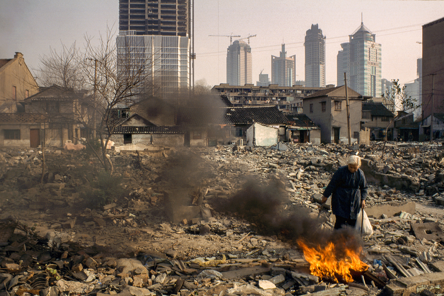 Preparing to vacate her home, an elderly resident burns discarded personal items, 1997.