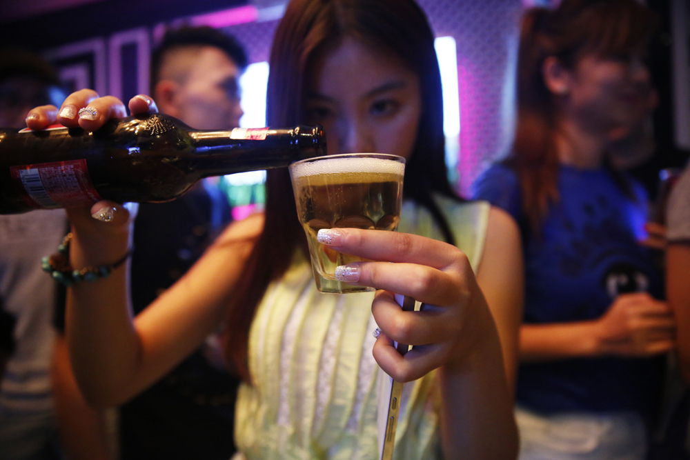 A woman invited by a student pours beer into a glass at the party, May 18, 2015.