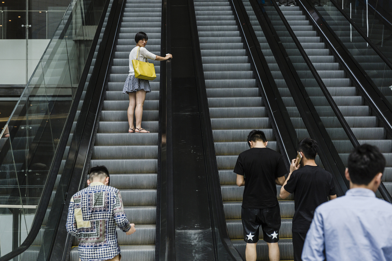 A woman glances at Puamap’s students on an escalator in a shopping mall, May 15, 2015. 