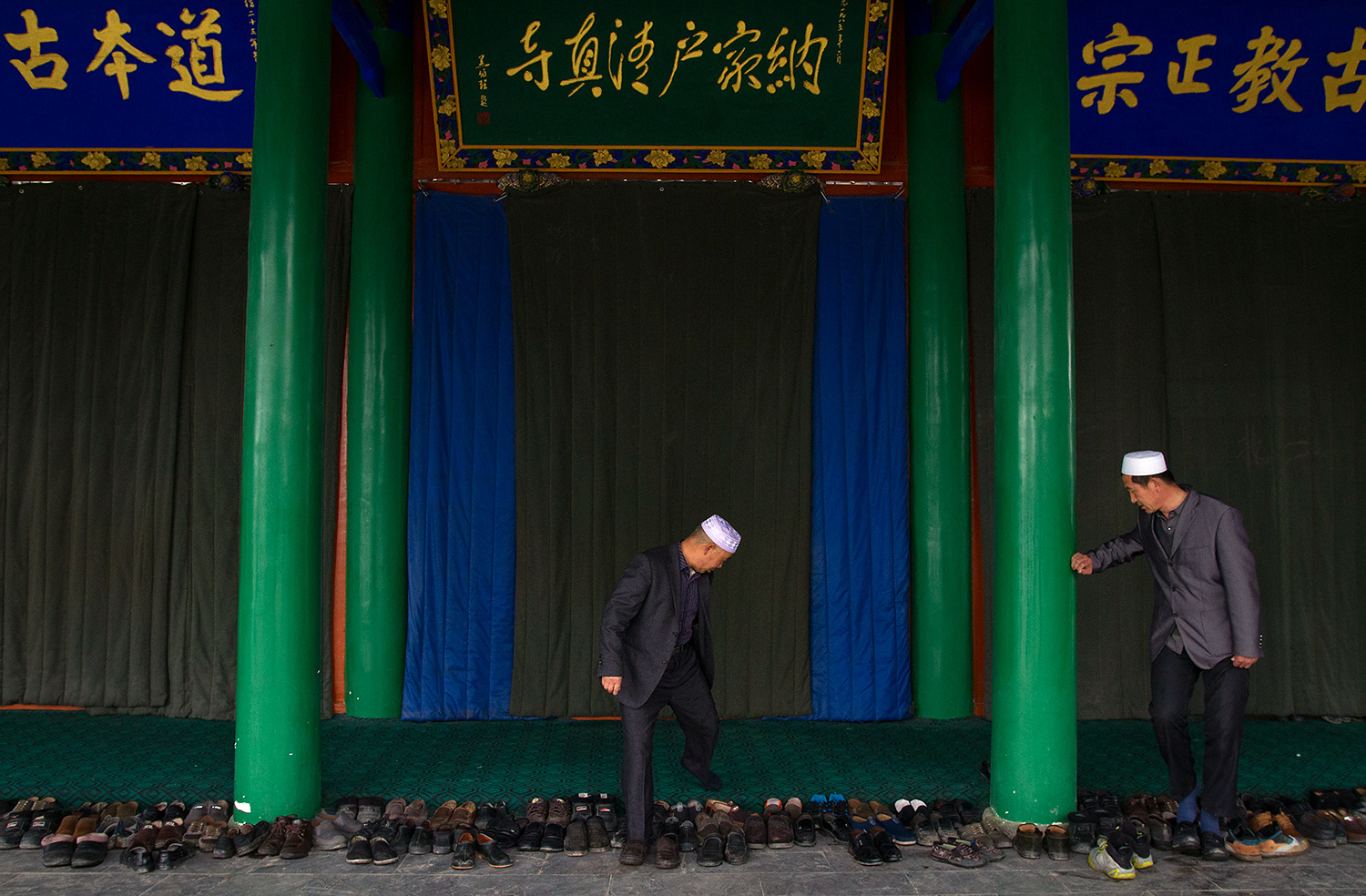 Two men leave their shoes at the entrance to the main prayer hall of Najiahu Mosque.